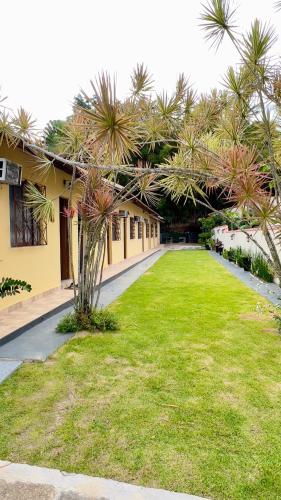 a yard with palm trees in front of a building at Pousada Villa Bella in Maricá