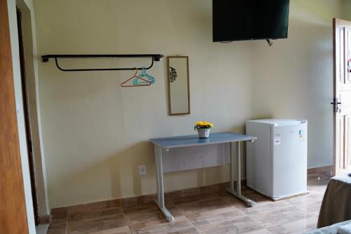 a table in a room with a small refrigerator at Pousada Villa Bella in Maricá