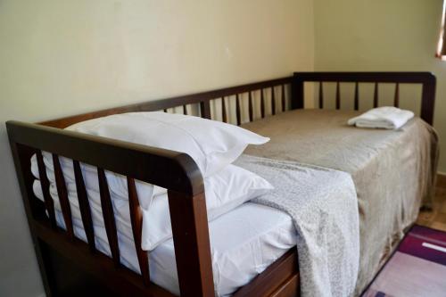 a wooden bed with white sheets and pillows on it at Pousada Villa Bella in Maricá
