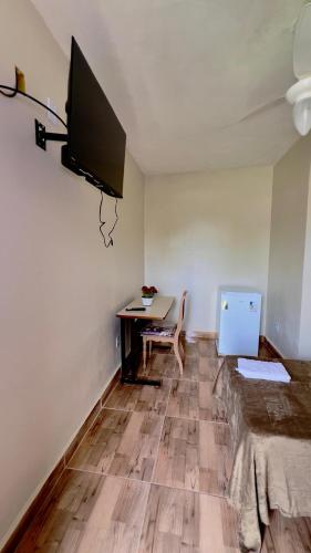 a room with a desk and a tv on a wall at Pousada Villa Bella in Maricá