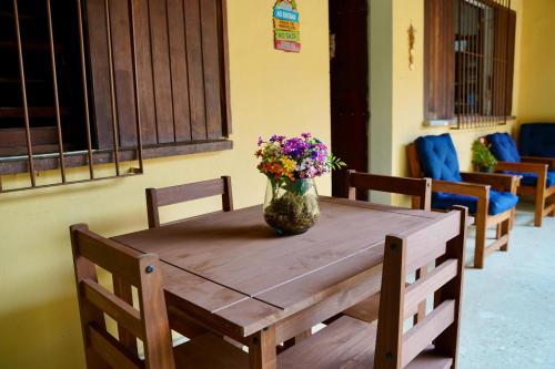 a wooden table with a vase of flowers on it at Pousada Villa Bella in Maricá