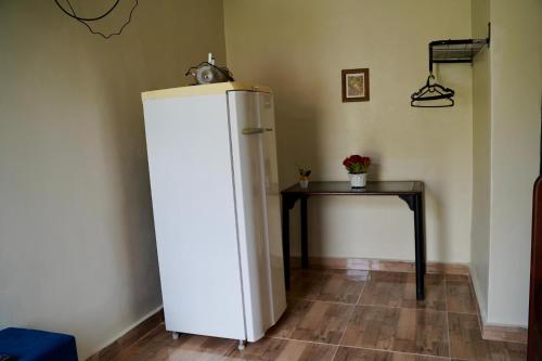 a white refrigerator and a table in a room at Pousada Villa Bella in Maricá