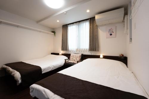 a hotel room with two beds and a window at Takasago Utopia Hotel in Tokyo