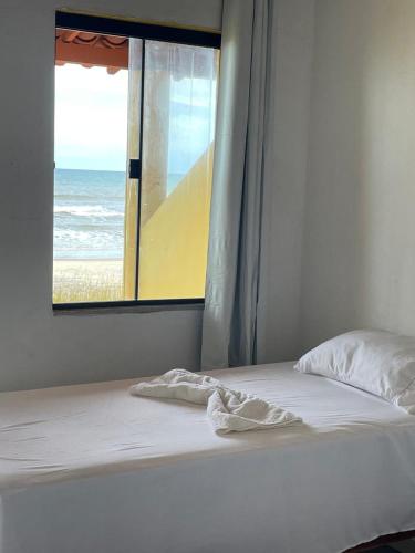 a bed with a window with a view of the beach at Tokaya Club in Ilhéus
