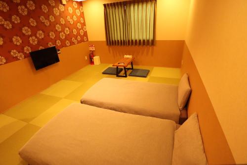 a small room with two beds and a tv at KYOSTAY Iroha Komichi in Kyoto