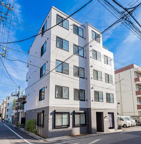 a tall white building on the side of a street at Wasabi Sky Oshiage 押上駅徒歩アパート in Tokyo