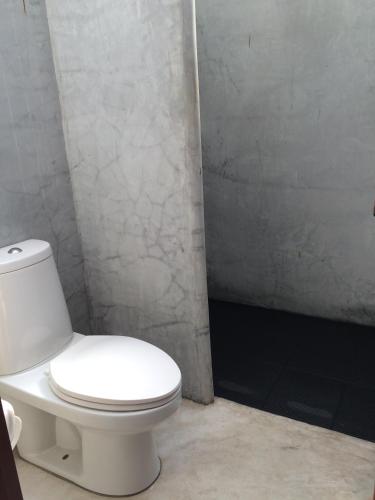 a bathroom with a white toilet in a room at Fern House Retreat in Chalong 