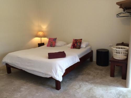 a bedroom with a bed with white sheets and pillows at Fern House Retreat in Chalong 