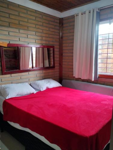 a bedroom with a large bed with a red blanket at Pousada e Residencial Linda in Capão da Canoa