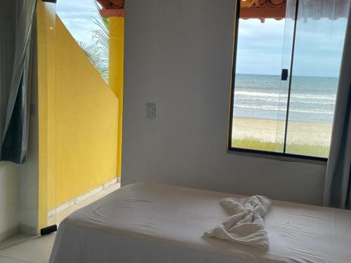 a bed in a room with a view of the beach at Tokaya Club in Ilhéus