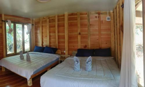 two beds in a room with wooden walls at อินทนนท์สุขุมทิพย์ โฮมสเตย์ in Ban Yang