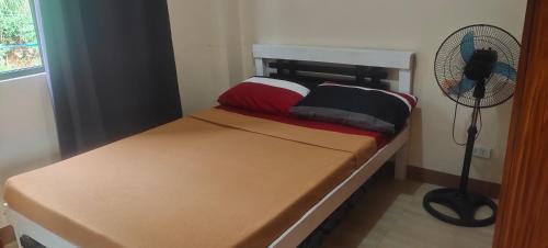 a small bedroom with a bed and a fan at Hut on the Hill Baguio City in Baguio