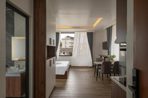 a hotel room with a bed and a table and a window at Anteaus Hotel Đà Lạt in Da Thien