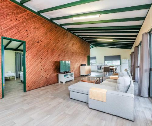 a living room with a couch and a tv at Endeavour - Rustic Two-Bedroom Home With Stunning Ocean & 1770 Headland Views in Seventeen Seventy