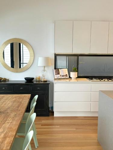 a kitchen with white cabinets and a table with a mirror at Mooloolaba Beach Haven in Mooloolaba