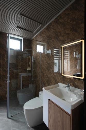 a bathroom with a sink and a toilet and a mirror at Anteaus Hotel Đà Lạt in Da Thien