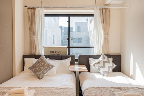 two beds in a room with a window at Wasabi Sky Oshiage 押上駅徒歩アパート in Tokyo