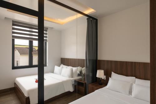 a bedroom with two beds and a mirror at Anteaus Hotel Đà Lạt in Da Thien