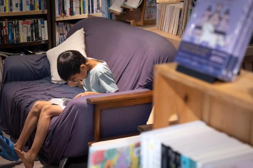 a man sitting on a couch reading a book at REST Book & Bed in Puli