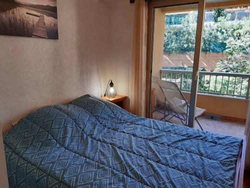 une chambre avec un lit avec une couette bleue et une fenêtre dans l'établissement Appartement 2P, 4 pers, terrasse, parking, plage à 250m - Bormes-les-Mimosas - FR-1-251-853, à Bormes-les-Mimosas