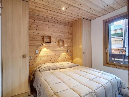 un lit dans une chambre avec un mur en bois dans l'établissement La Clusaz - Appartement cosy pour 4 pers avec balcon et WIFI - FR-1-818-11, à La Clusaz