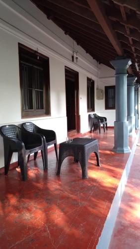 a room with black chairs on a red floor at Perch Next door in Kannur