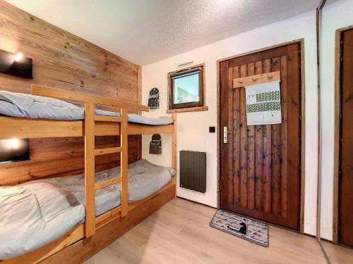 Cette chambre comprend 2 lits superposés et une porte. dans l'établissement Studio rénové pour 5 à La Clusaz avec balcon et parking - FR-1-818-29, à La Clusaz