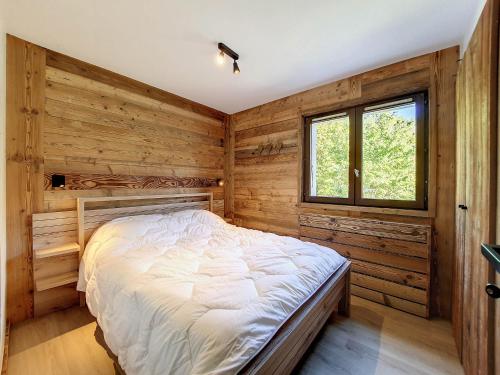 Ce lit se trouve dans un dortoir doté de murs en bois et d'une fenêtre. dans l'établissement La Clusaz: Appartement 6 pers, 2 chambres, balcon, garage - FR-1-818-30, à La Clusaz