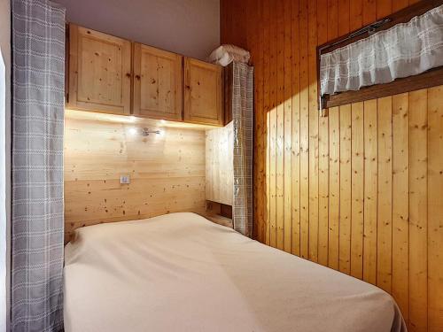 Ce lit se trouve dans un dortoir doté de murs et de placards en bois. dans l'établissement Charmant appart 4 pers, balcon sud, garage, WiFi, La Clusaz - FR-1-818-67, à La Clusaz