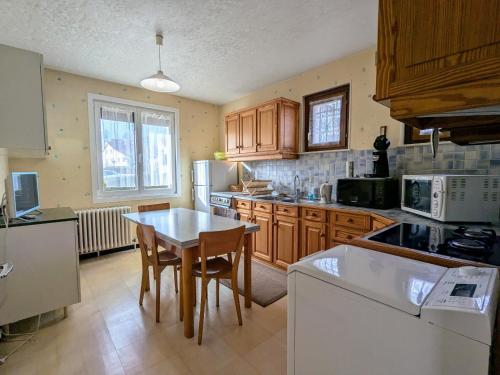 une cuisine avec des armoires en bois et une table avec des chaises dans l'établissement Maison à Gérardmer avec vue sur montagnes, garage et jardin - FR-1-589-776, à Gérardmer