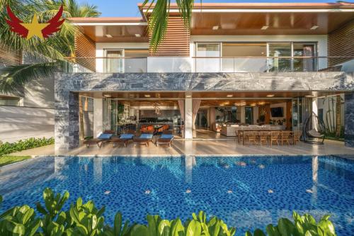 a house with a swimming pool in front of a house at The Five Stars Villa 8 Bedrooms Beachfront in Danang