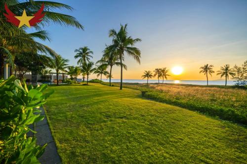 a park with palm trees and the ocean at sunset at The Five Stars Villa 8 Bedrooms Beachfront in Danang
