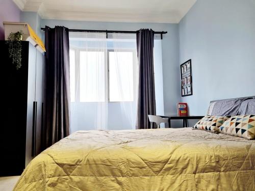 Un dormitorio con una cama con un edredón amarillo y una ventana. en 3R2B Homestay Puchong behind Bandar Puteri, en Puchong