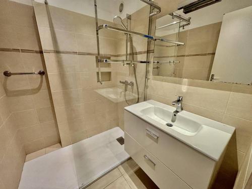 une salle de bain blanche avec un lavabo et une douche dans l'établissement Appartement lumineux avec terrasse et accès plage - FR-1-816-15, au Lavandou