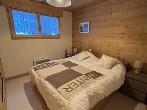 une chambre avec un lit et un mur en bois dans l'établissement Appartement spacieux avec balcon sud et parking couvert - FR-1-692-110, à La Chapelle-dʼAbondance