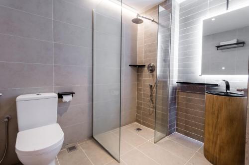 a bathroom with a toilet and a glass shower at Regatta at Kozi Square Kuching in Kuching
