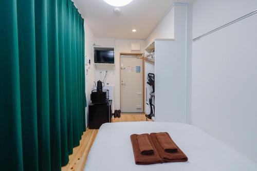 a room with a bed with a green curtain at Zenith Shinjuku Hinoki by Tranova in Tokyo