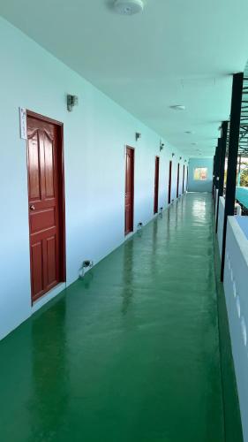 a long corridor with green flooring in a building at กุลทีปโฮสเทล in Pathum Thani