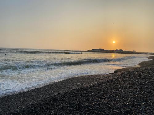 a beach with the ocean and the sunset in the background at Departamento in Magdalena del Mar in Lima