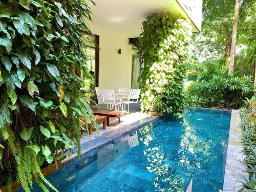 a swimming pool in a garden with a ivy covered wall at FLAMIGO Đại Lải - Villa Tự Doanh in Phúc Yên