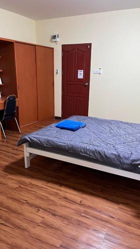 a bedroom with a bed with a blue blanket on it at กุลทีปโฮสเทล in Pathum Thani
