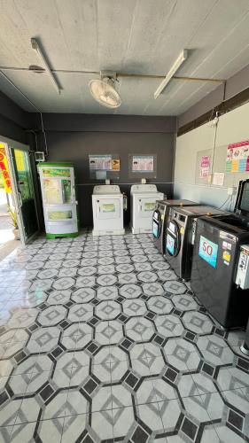 a laundry room with three washing machines and a tile floor at กุลทีปโฮสเทล in Pathum Thani