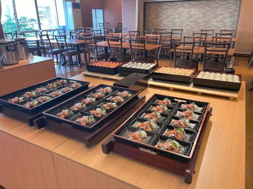 a buffet line with trays of food in a restaurant at Itoen Hotel in Ito