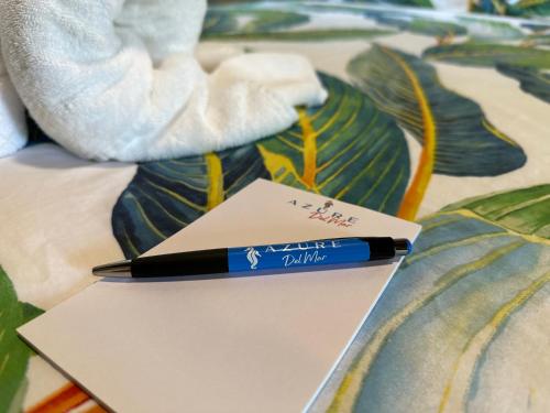 a pen sitting on top of a paper on a bed at Azure Del Mar in Maya Beach