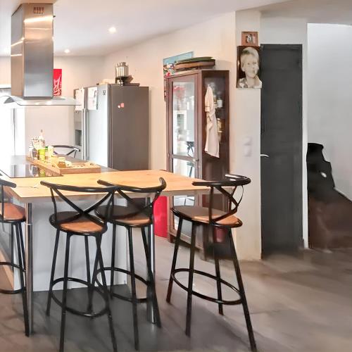 une cuisine avec une table en bois et quatre tabourets dans l'établissement Maison charmante à Prat-Bonrepaux avec vue sur la montagne, à Prat-et-Bonrepaux