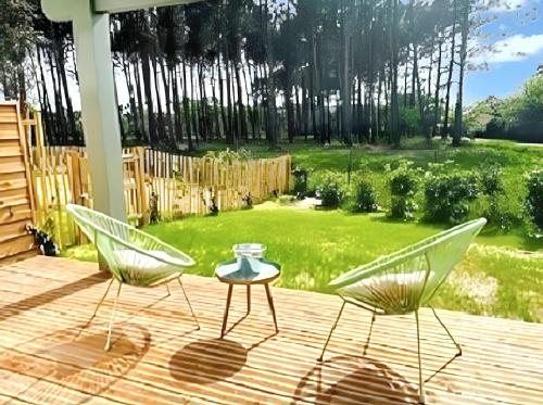 two chairs and a table on a deck with a yard at Maison élégante à Moliets-et-Maa avec jardin clos et terrasse in Moliets-et-Maa