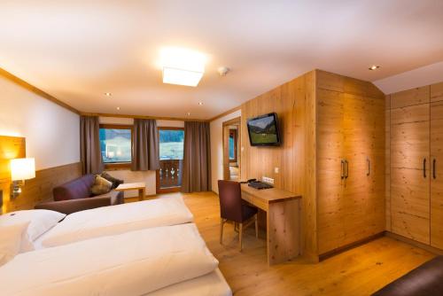 una camera d'albergo con 2 letti e una scrivania di Hotel Dorfer a Grossarl