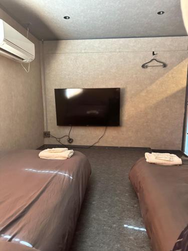 a room with two beds and a flat screen tv at Grandblue HARVELKITICHEN in Tokashiki
