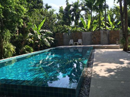 basen z niebieskimi płytkami na podwórku w obiekcie Fern House Retreat w mieście Chalong
