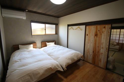 a bedroom with a large white bed and a window at 阿蘇のおばあちゃん家 in Aso